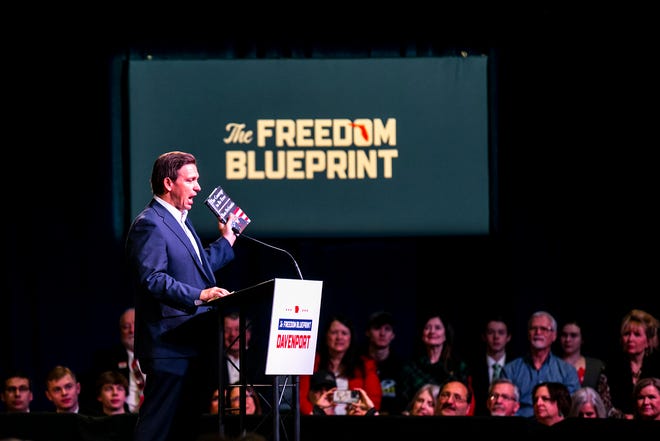 Florida Gov. Ron DeSantis holds a copy of his book "The Courage to be Free" as he speaks with Iowa Gov. Kim Reynolds during the Freedom Blueprint Event, Friday, March 10, 2023, at Rhythm City Casino Resort in Davenport, Iowa.