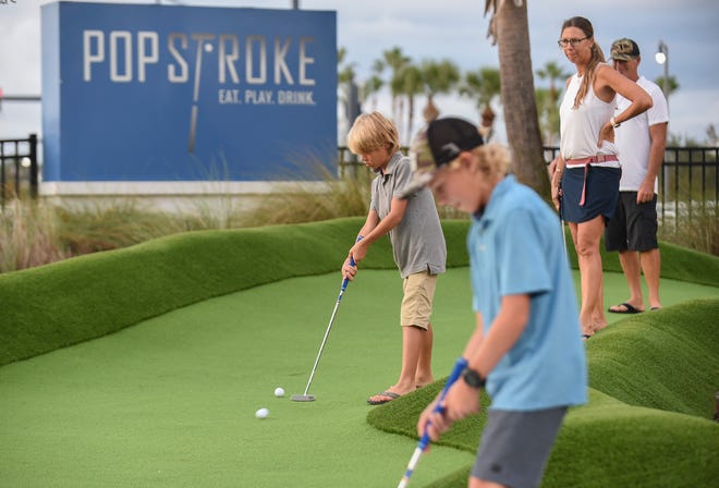 Blake Strube, 8 (in gray), makes a putting shot on the back hole of the Red Course with his brother Everett, 11, and parents Jen and Tim Strube as the family from Stuart plays the Red course at PopStroke on Monday, Oct. 10, 2022, in the Tradition development in Port St. Lucie. Two new Tiger Woods redesigned 18-hole courses, Red and Black, replaced the previous courses. "It's great, It's nice to have something like this so close to home. It gives the kids a chance to practice their putting skills," Jen Strube said.