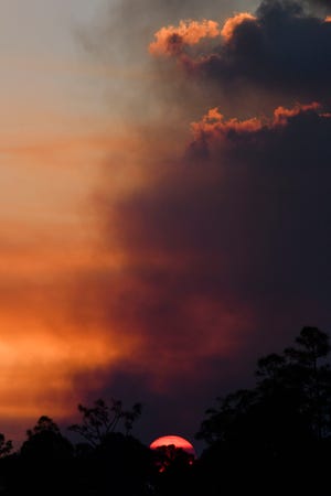 The sun sets as a wildfire burns Thursday evening March 23, 2023, in the John C. and Mariana Jones/Hungryland Wildlife and Environmental Area off Pratt Whitney Road in Martin County near Indiantown.