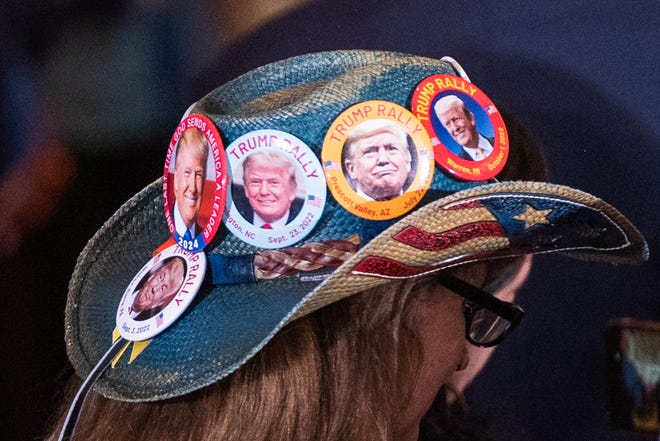 A guest wears a hat decorated with buttons displaying images of former President Donald Trump inside the Mar-A-Lago main ballroom before the start of a press event at Mar-A-Lago on Tuesday, April 4, 2023, in Palm Beach FL. Trump returned to Mar-A-Lago Tuesday evening after facing arraignment in New York earlier in the day.